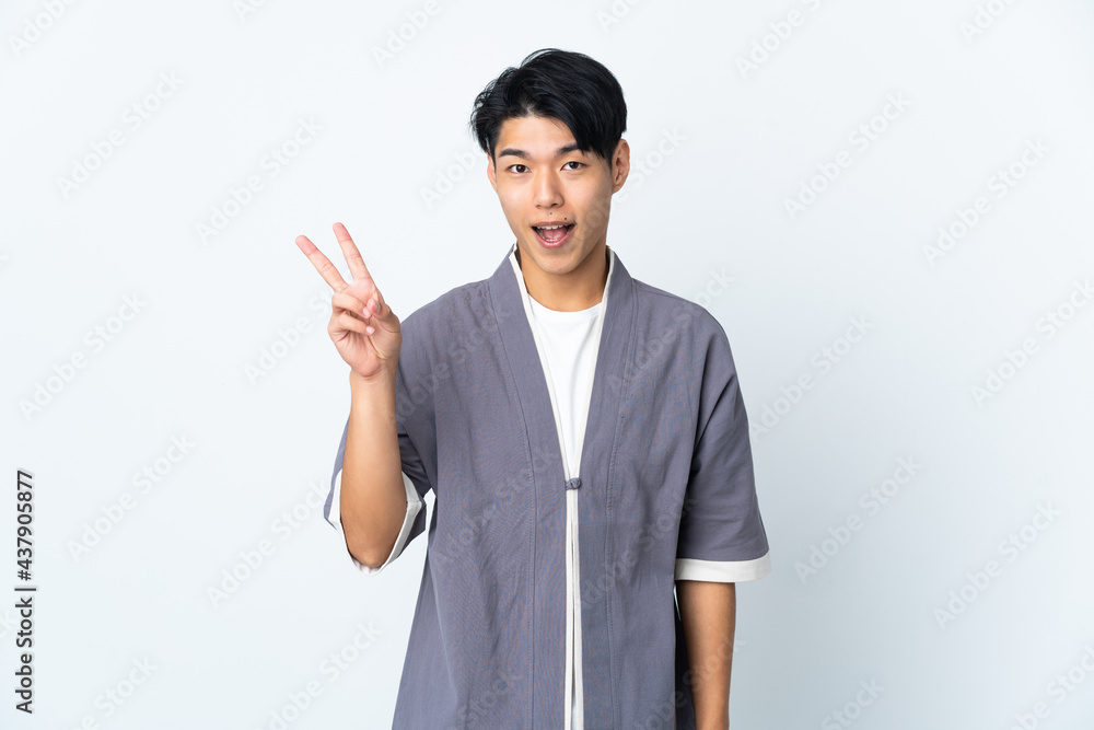 Young Chinese man isolated on white background smiling and showing victory sign Young Chinese man isolated on white background smiling and showing victory sign