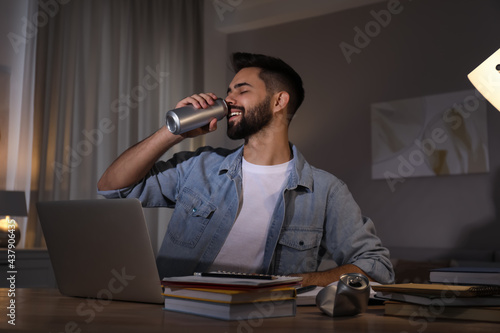 Young man with energy drink studying at home