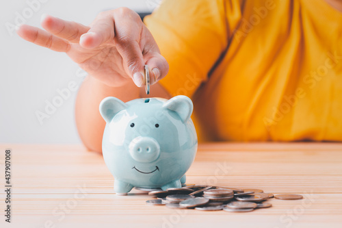 Save money, Woman hand putting coins into blue piggy bank for account save money, Planning step up growth saving money for future, retirement fund, business investment finance accounting concept.