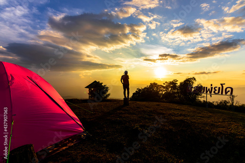 Silhouette of tent with tourists relaxing on view point during beautiful sunset time of Doi Pui Ko mountain in Mae Hong Son ,Thailand. (Doi Pui Ko word is name in Thai language on board)