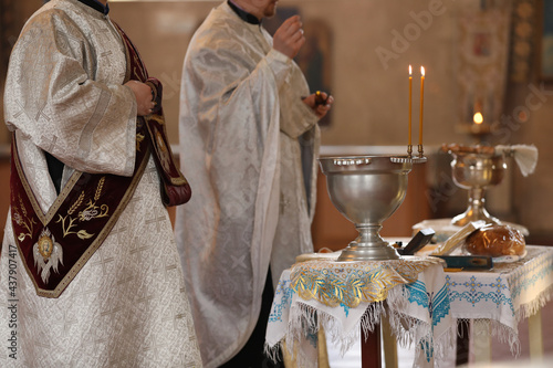 MYKOLAIV, UKRAINE - FEBRUARY 27, 2021: Deacon and priest conducting baptism ceremony in Kasperovskaya icon of Mother of God cathedral, closeup photo
