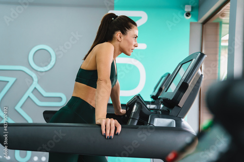 White brunette sportswoman working out on treadmill in gym