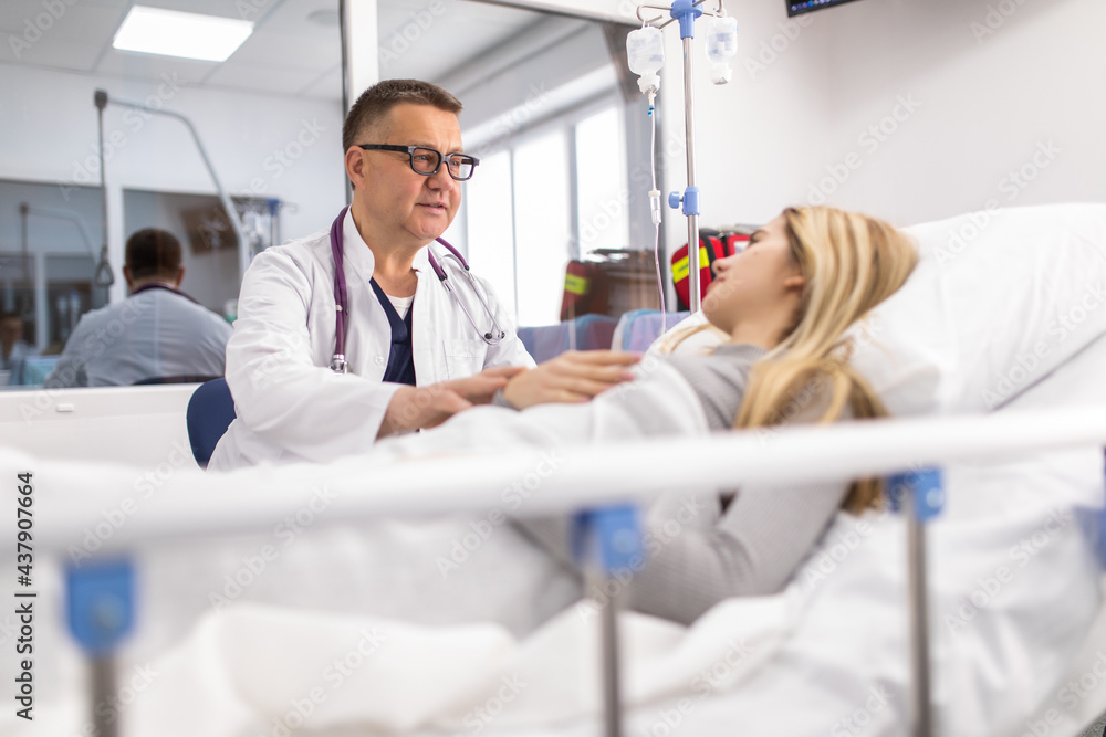 Mature man doctor reassuring his female patient in bed at hospital. Medical ethics and trust concept. Mature man doctor reassuring his female patient in bed at hospital. Medical ethics and trust concept.