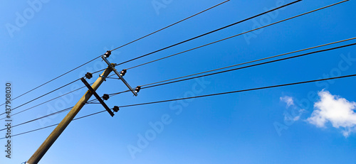 Electric pole with blue sky background. a stand-alone electric pylon with power lines sticking through the sky.