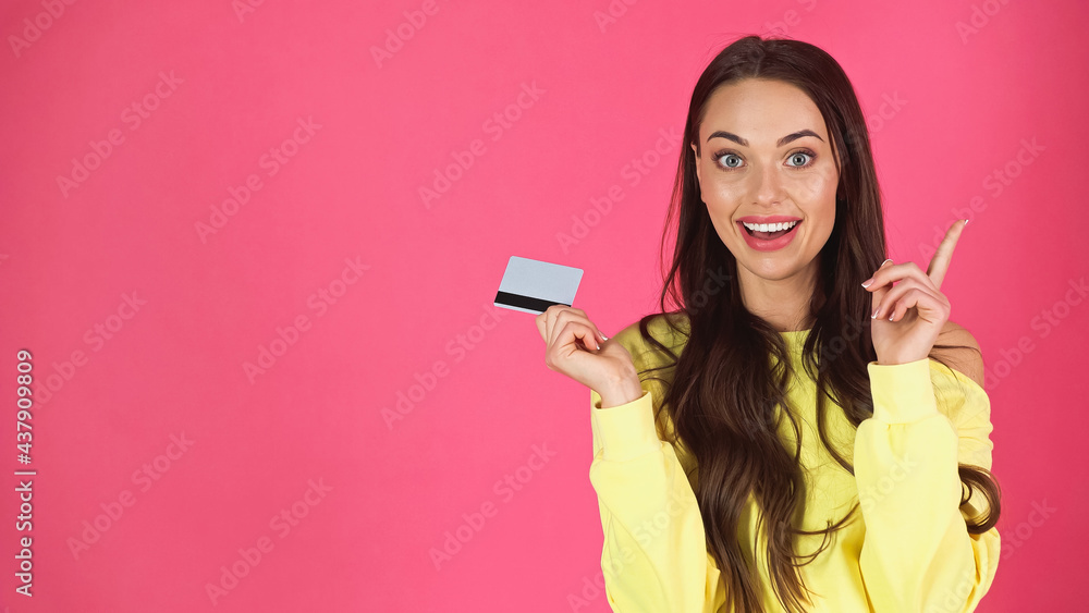 Naklejka premium excited young adult woman holding credit with idea gesture isolated on pink