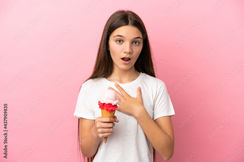 Little girl with a cornet ice cream over isolated pink background surprised and shocked while looking right