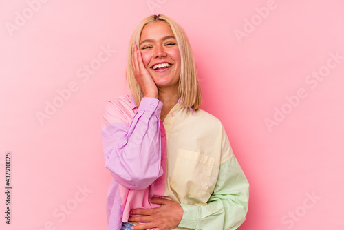 Young venezuelan woman isolated on pink background laughs happily and has fun keeping hands on stomach.