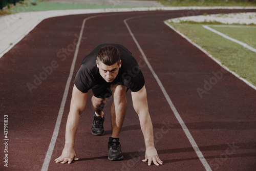 Man standing in low start position on the running track at stadium