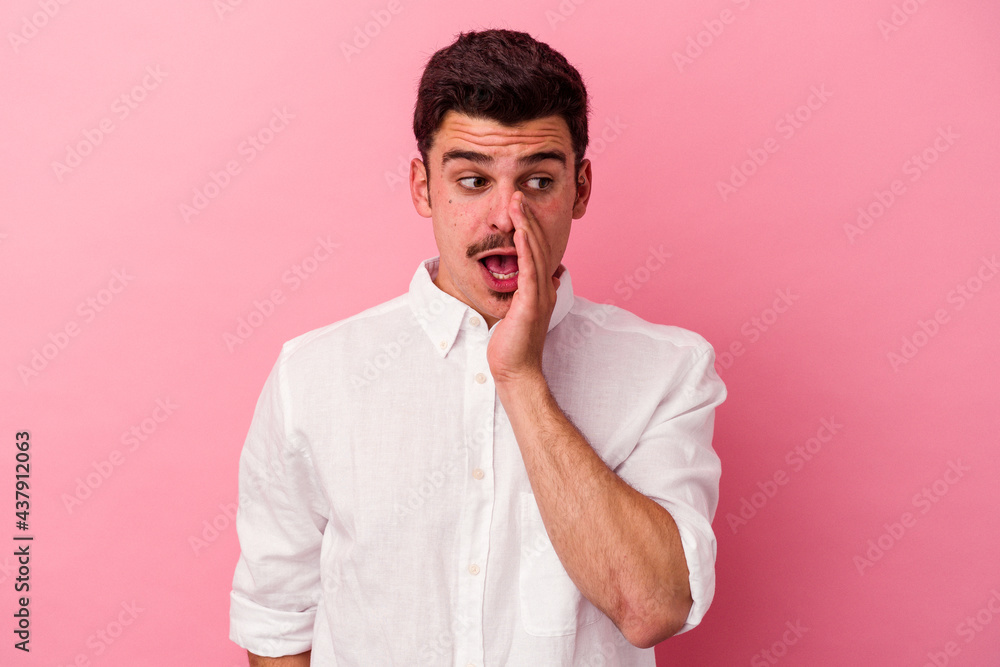 Young caucasian man isolated on pink background is saying a secret hot braking news and looking aside Young caucasian man isolated on pink background is saying a secret hot braking news and looking aside