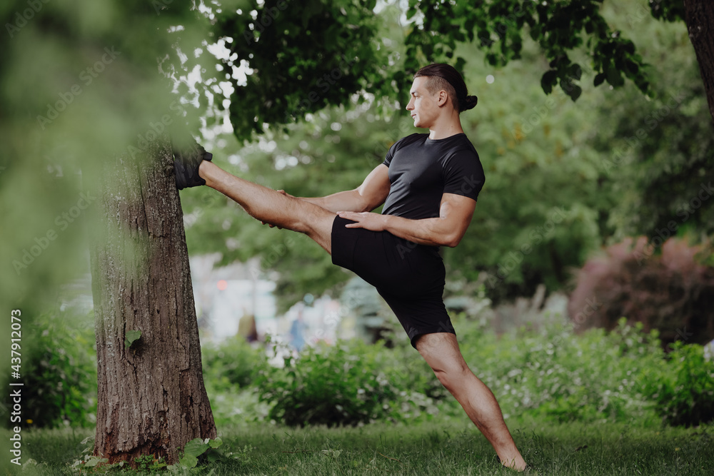 Sport fit man stretching legs near tree in a park Sport fit man stretching legs near tree in a park