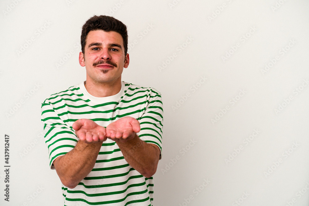 Young caucasian man isolated on white background folding lips and holding palms to send air kiss. Young caucasian man isolated on white background folding lips and holding palms to send air kiss.