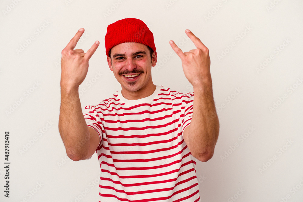 Young caucasian man isolated on white background showing a horns gesture as a revolution concept. Young caucasian man isolated on white background showing a horns gesture as a revolution concept.