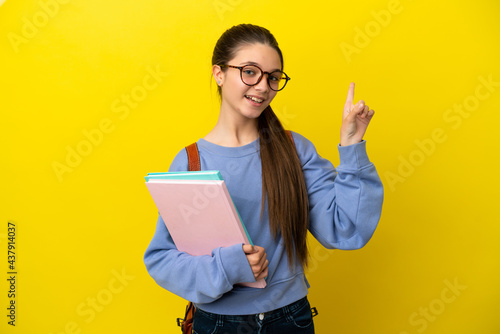 Student kid woman over isolated yellow background showing and lifting a finger in sign of the best