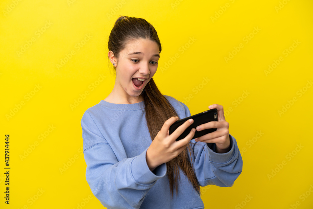 Little girl over isolated yellow background playing with the mobile phone Little girl over isolated yellow background playing with the mobile phone