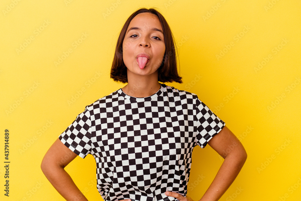 Young mixed race woman isolated on yellow background funny and friendly sticking out tongue. Young mixed race woman isolated on yellow background funny and friendly sticking out tongue.