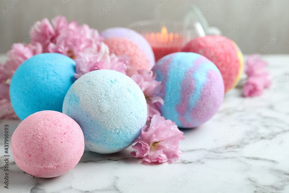 Fragrant bath bombs and sakura flowers on white marble table Fragrant bath bombs and sakura flowers on white marble table