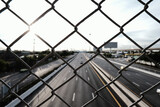 Transport and logistics industry. Wire mesh fence with highway background. Motorway road. The concept of lockdown the city and restricting travel.