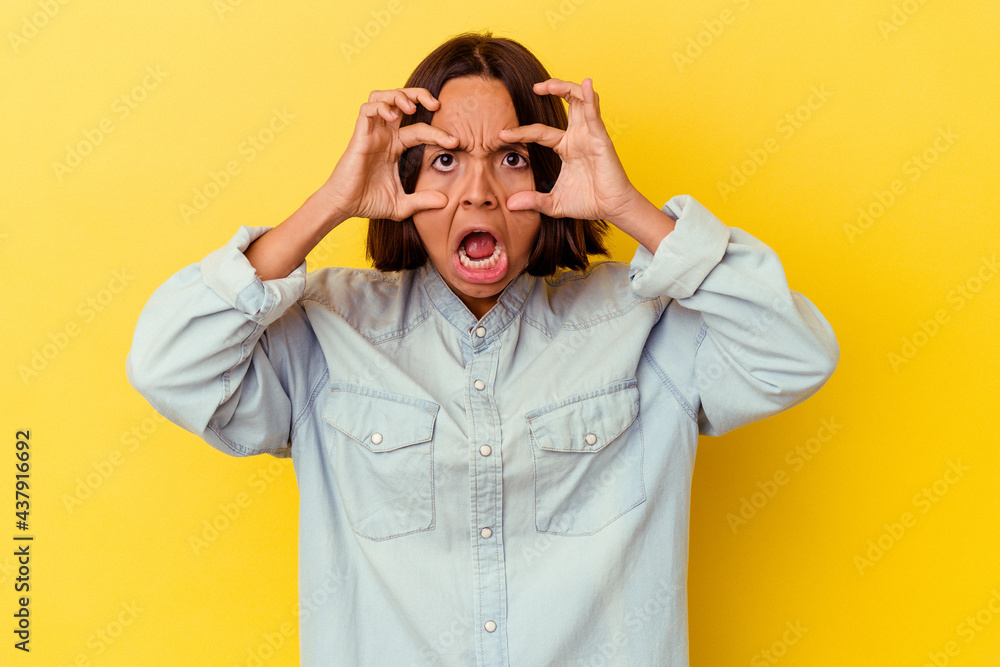 Young mixed race woman isolated on yellow background keeping eyes opened to find a success opportunity. Young mixed race woman isolated on yellow background keeping eyes opened to find a success opportunity.