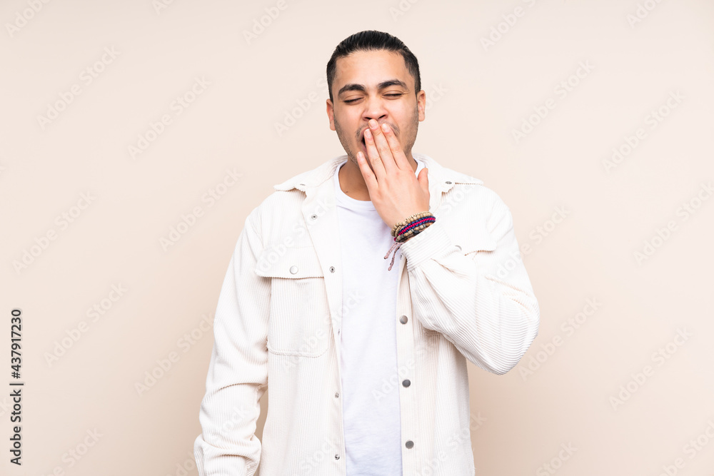 Asian handsome man over isolated background yawning and covering wide open mouth with hand Asian handsome man over isolated background yawning and covering wide open mouth with hand