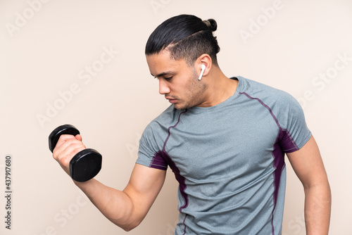 Asian sport man isolated on beige background making weightlifting