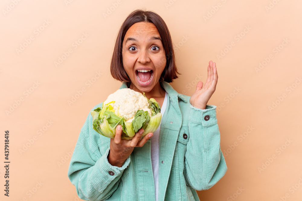Young mixed race woman holding a cabbage isolated on beige background Young mixed race woman holding a cabbage isolated on beige background