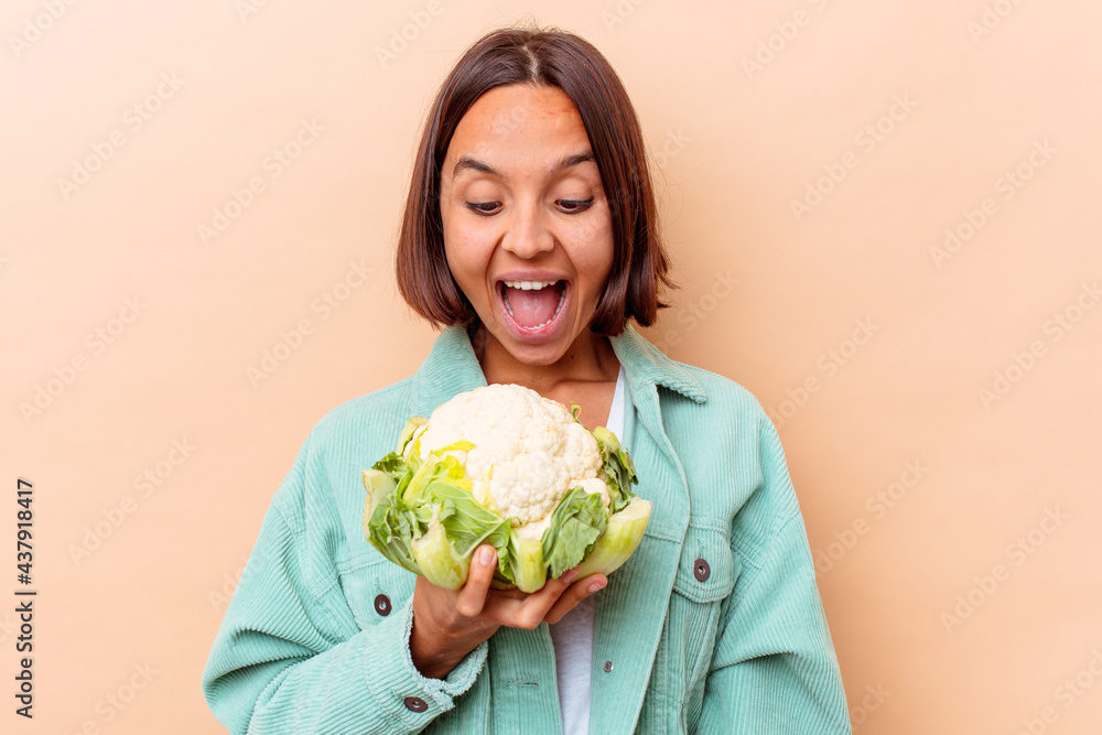 Young mixed race woman holding a cabbage isolated on beige background Young mixed race woman holding a cabbage isolated on beige background