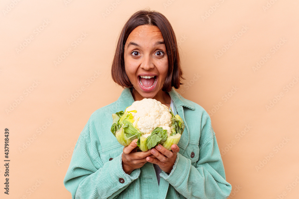 Young mixed race woman holding a cabbage isolated on beige background Young mixed race woman holding a cabbage isolated on beige background