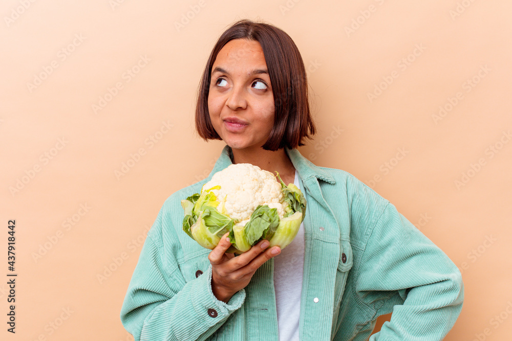 Young mixed race woman holding a cabbage isolated on beige background Young mixed race woman holding a cabbage isolated on beige background