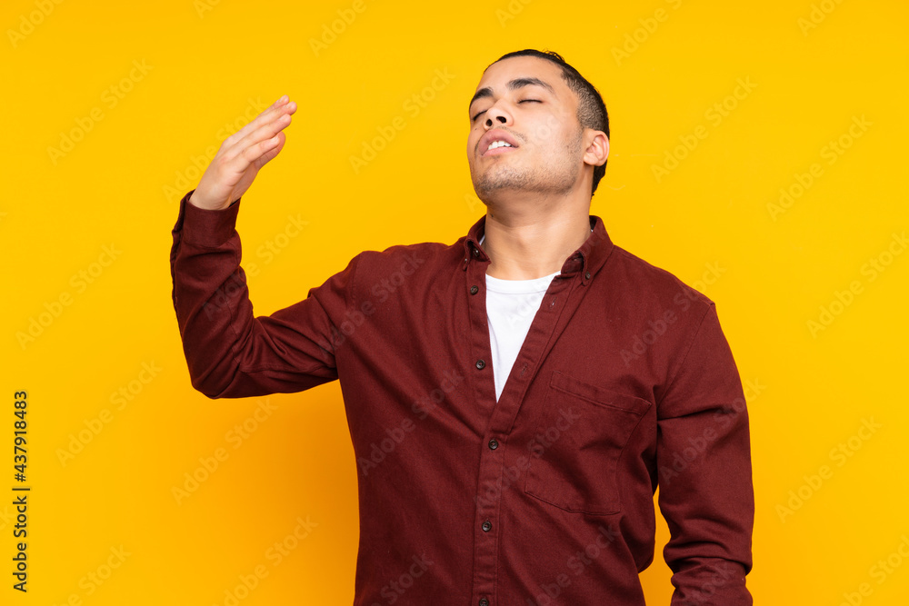 Asian handsome man isolated on yellow background extending hands to the side for inviting to come Asian handsome man isolated on yellow background extending hands to the side for inviting to come
