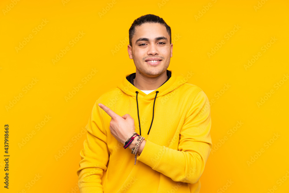 Asian handsome man isolated on yellow background saluting with hand with happy expression Asian handsome man isolated on yellow background saluting with hand with happy expression