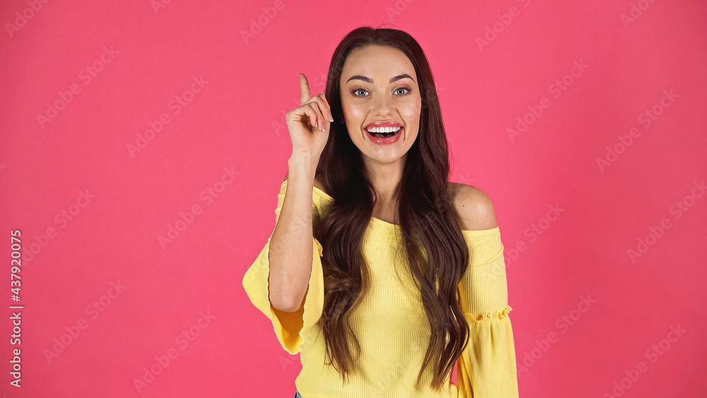 smiling young adult woman in yellow blouse pointing with finger isolated on pink smiling young adult woman in yellow blouse pointing with finger isolated on pink