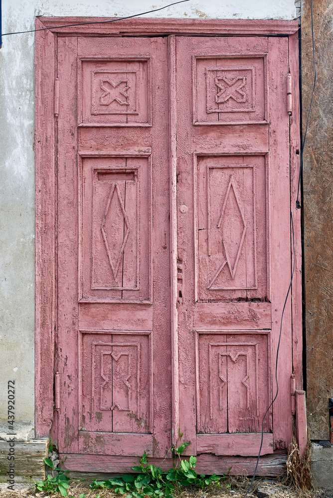 An old dark pink wooden door on the stone wall.