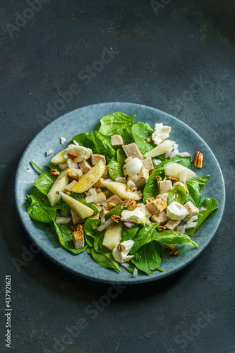 Pork with pear, spinach and soft cheese salad on dark background