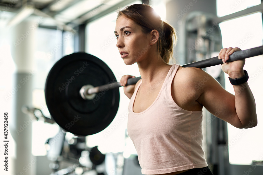 Determined female athlete having weight training in a gym. Determined female athlete having weight training in a gym.