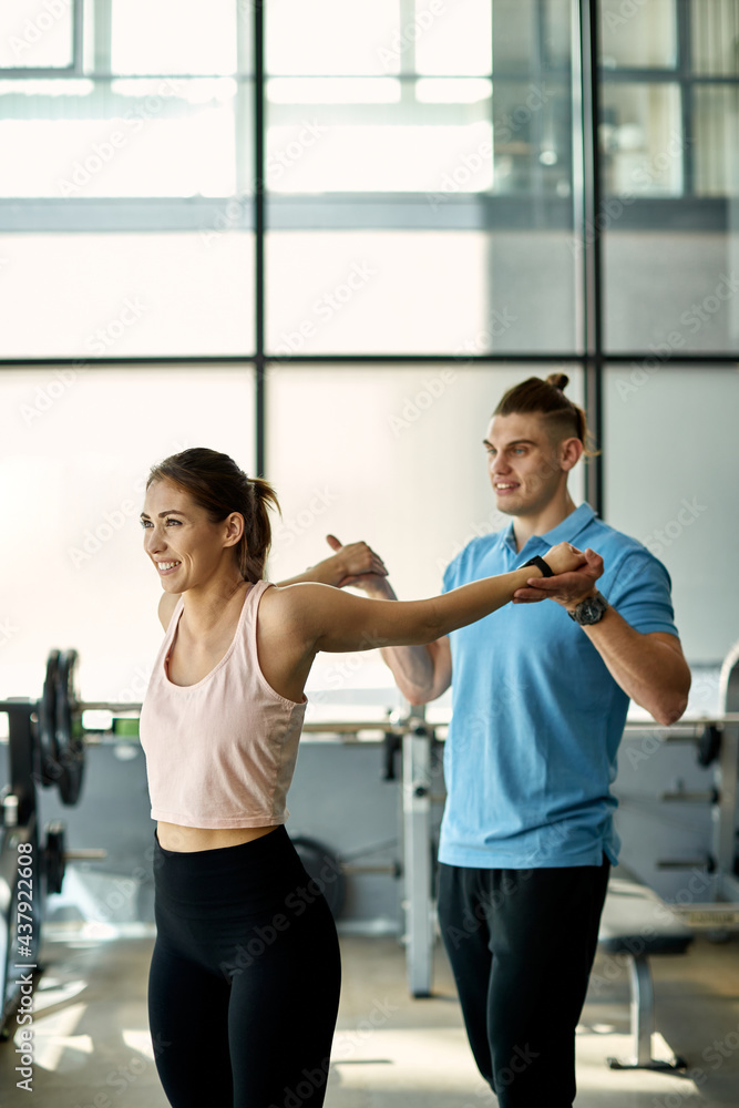 Fitness instructor stretching woman's arms after sports training in a gym. Fitness instructor stretching woman's arms after sports training in a gym.