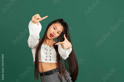 Asian young woman's portrait isolated over color studio background with copyspace