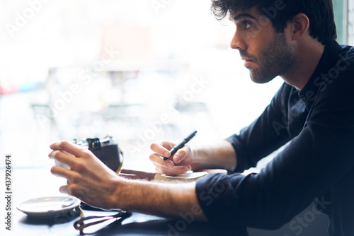 Adult handsome man sitting in cafe and interviewing anonymous person