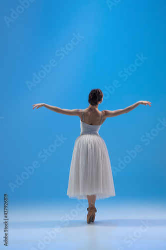 Young and incredibly beautiful ballerina is posing and dancing at blue studio full of light. © master1305