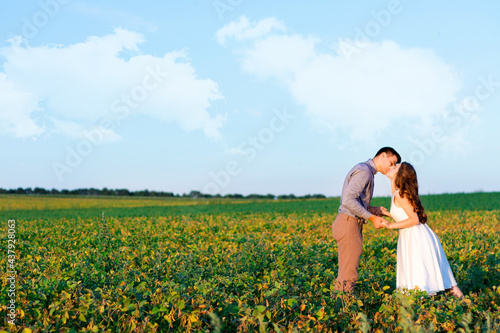 Young romantic wedding couple are posing on grass field. Happy loveling woman and man are walking together at beautiful nature on summer day. Love story concept. Template for invitation  greeting card