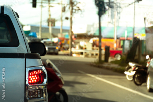 Rear side of pickup car silver color driving on the road in the city. Blurred image of intersection on road.