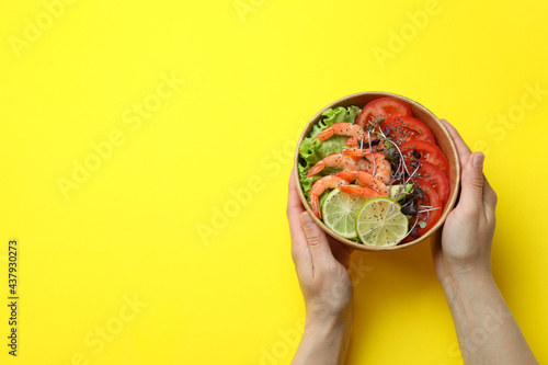 Concept of tasty eating with shrimp salad on yellow background