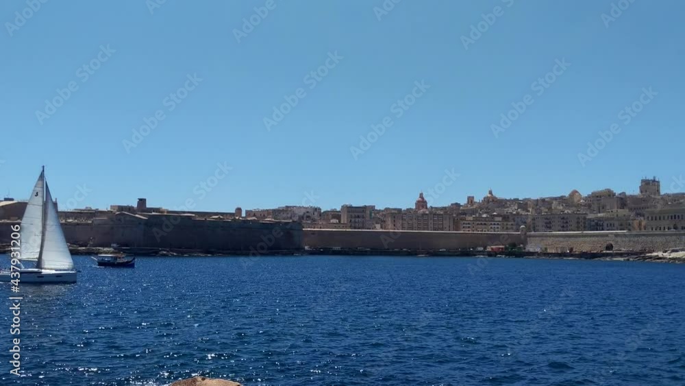 White yacht sailing and racing small traditional luzzu boat in blue sea water with Valletta city in background, Malta, 4K White yacht sailing and racing small traditional luzzu boat in blue sea water with Valletta city in background, Malta, 4K