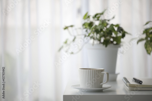 white coffee cup and plant pot on white table minimal interior