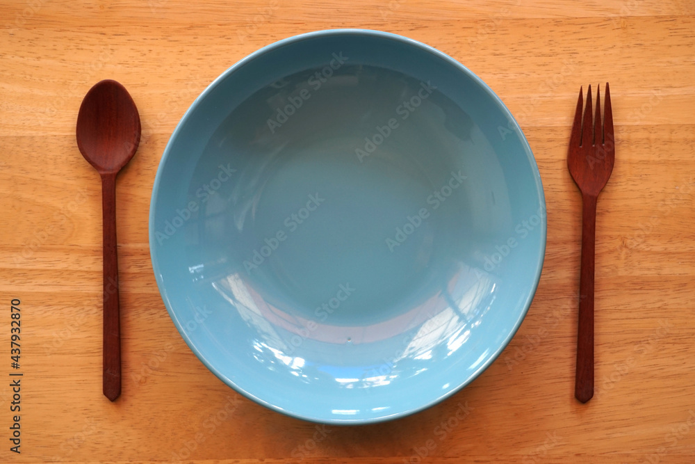 Empty blue plate with spoon and fork on wood background. Empty blue plate with spoon and fork on wood background.