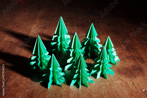 Origami trees isolated on dark background with long shadow.