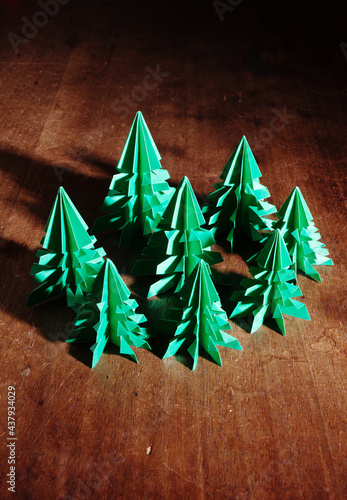 Origami trees isolated on dark background with long shadow.