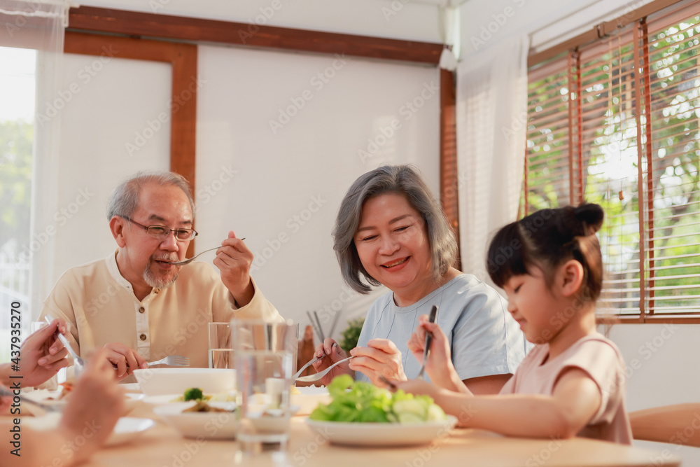 Asian extended family having breakfast together at home. Asian Big family grandparents parents and kid enjoy eating and talking with happy moment.