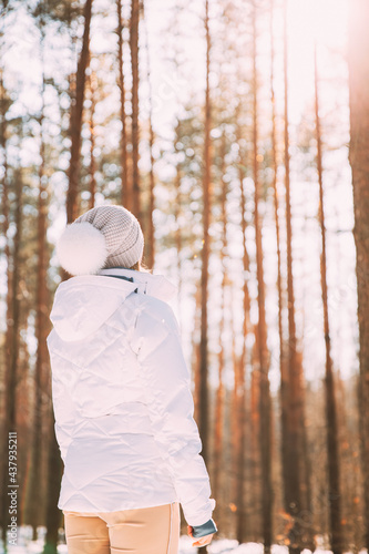 Young Single Woman Lady Standing In White Jacket And Hat In Forest And Looking Into Distance In Pine Wood. Back View. power of women