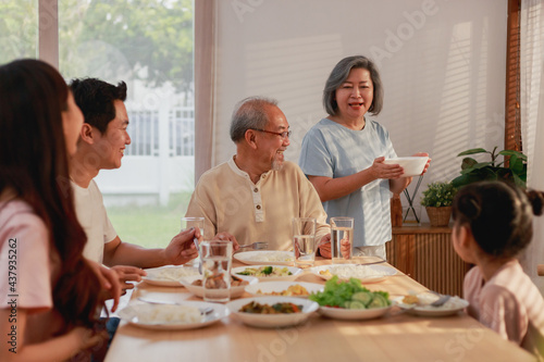 Asian extended family having breakfast together at home. Asian Big family grandparents parents and kid enjoy eating and talking with happy moment.