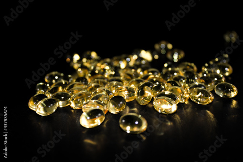 Group of spilled cod liver capsules isolated on black background